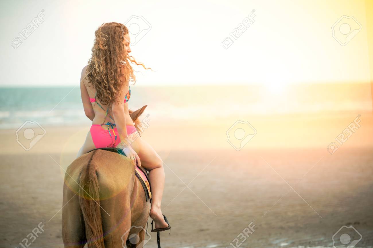 Woman fashion model riding a horse on the beach in summer. Luxury travel vacation. - 105392428