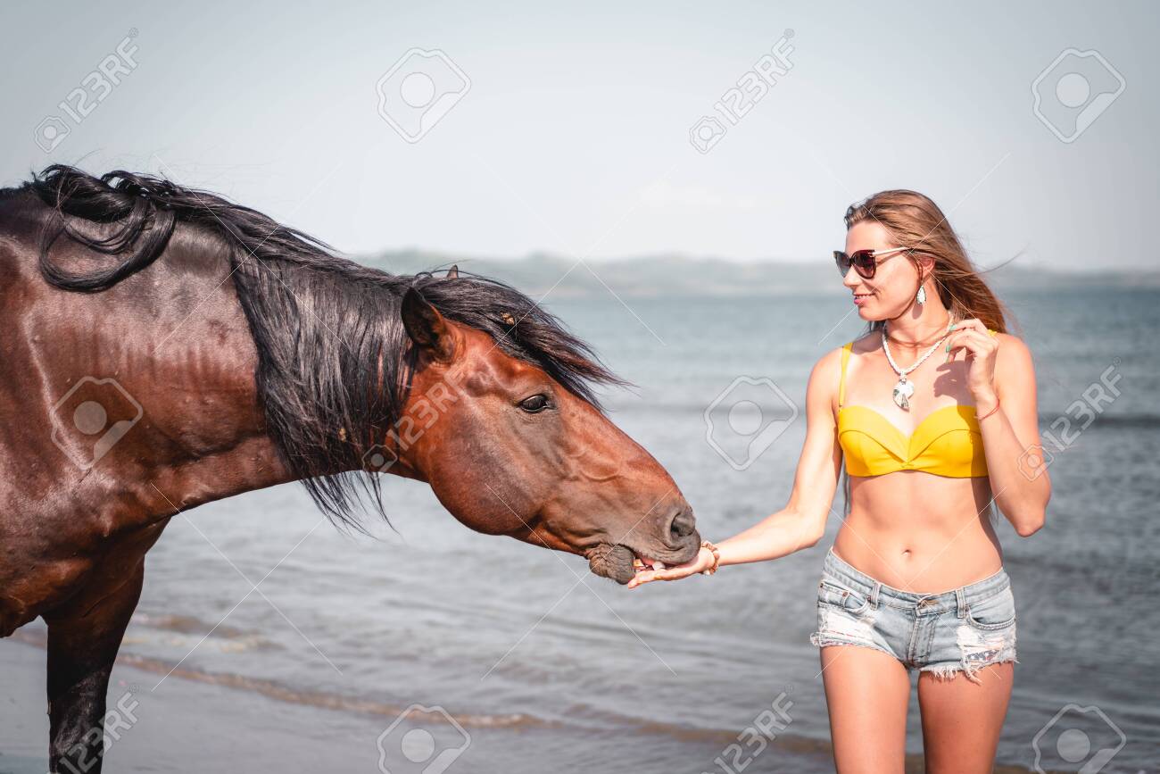 Portrait of smiling woman and a horse on the beach - 131536091