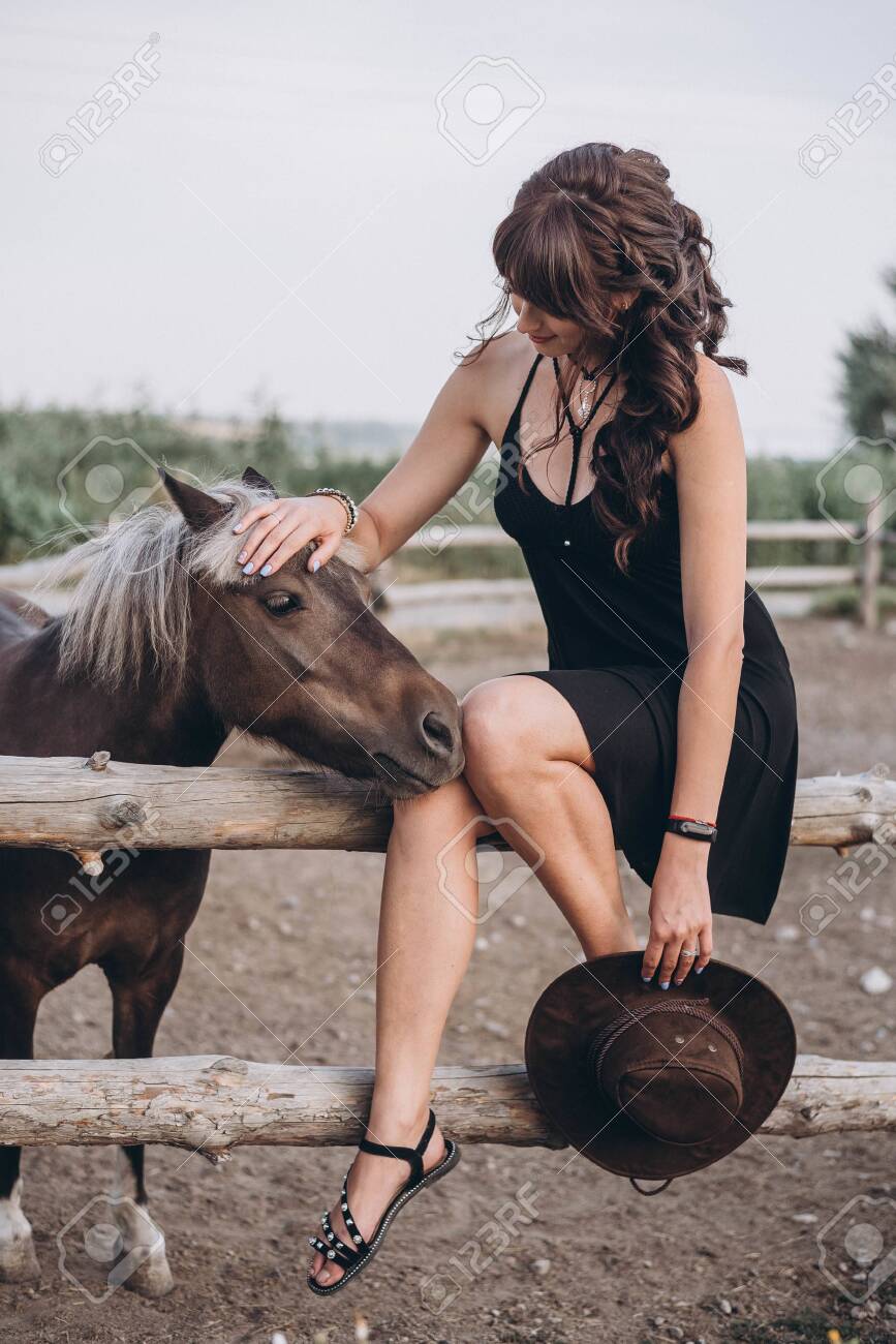 beautiful young girl near horse on ranch. A woman looks at a horse. Portrait of a girl with a horse - 146376336