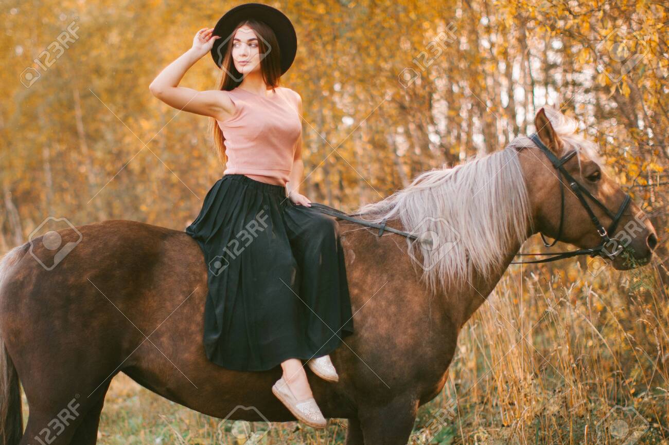 Girl in a hat riding a horse in nature. - 158352061