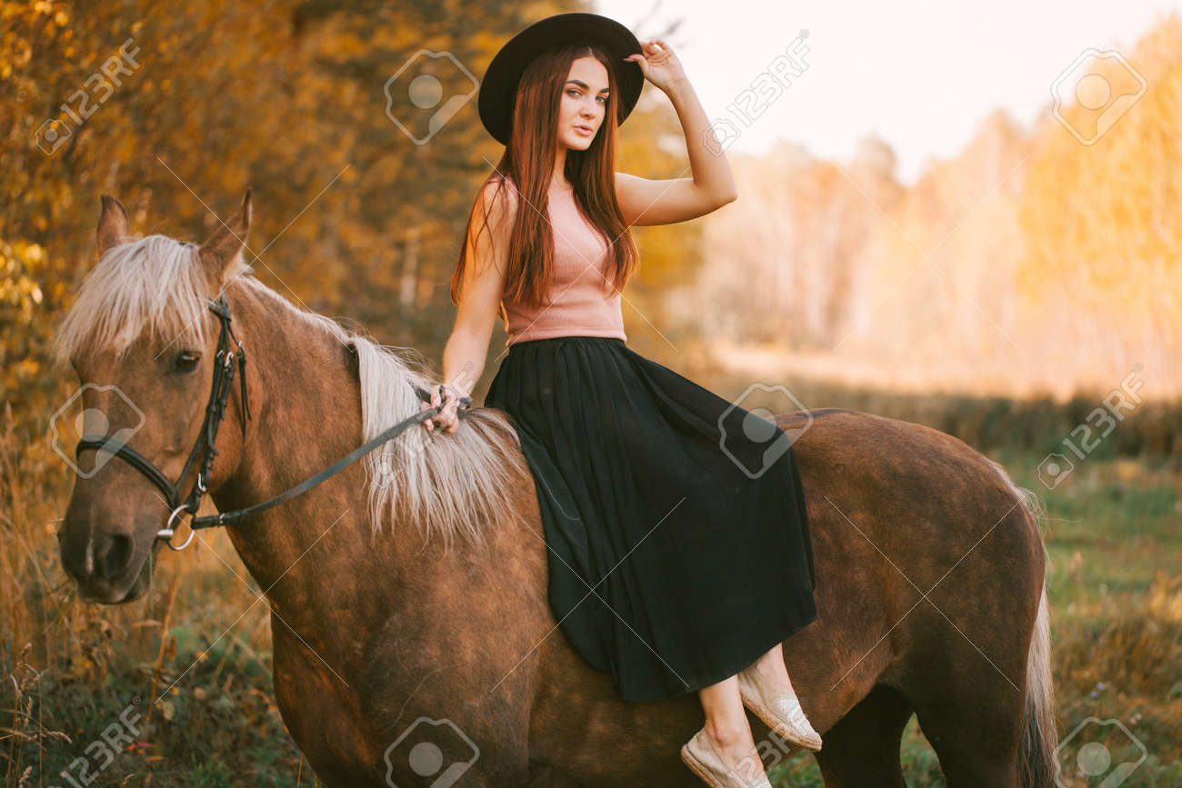 Girl in a hat riding a horse in nature. - 158352084