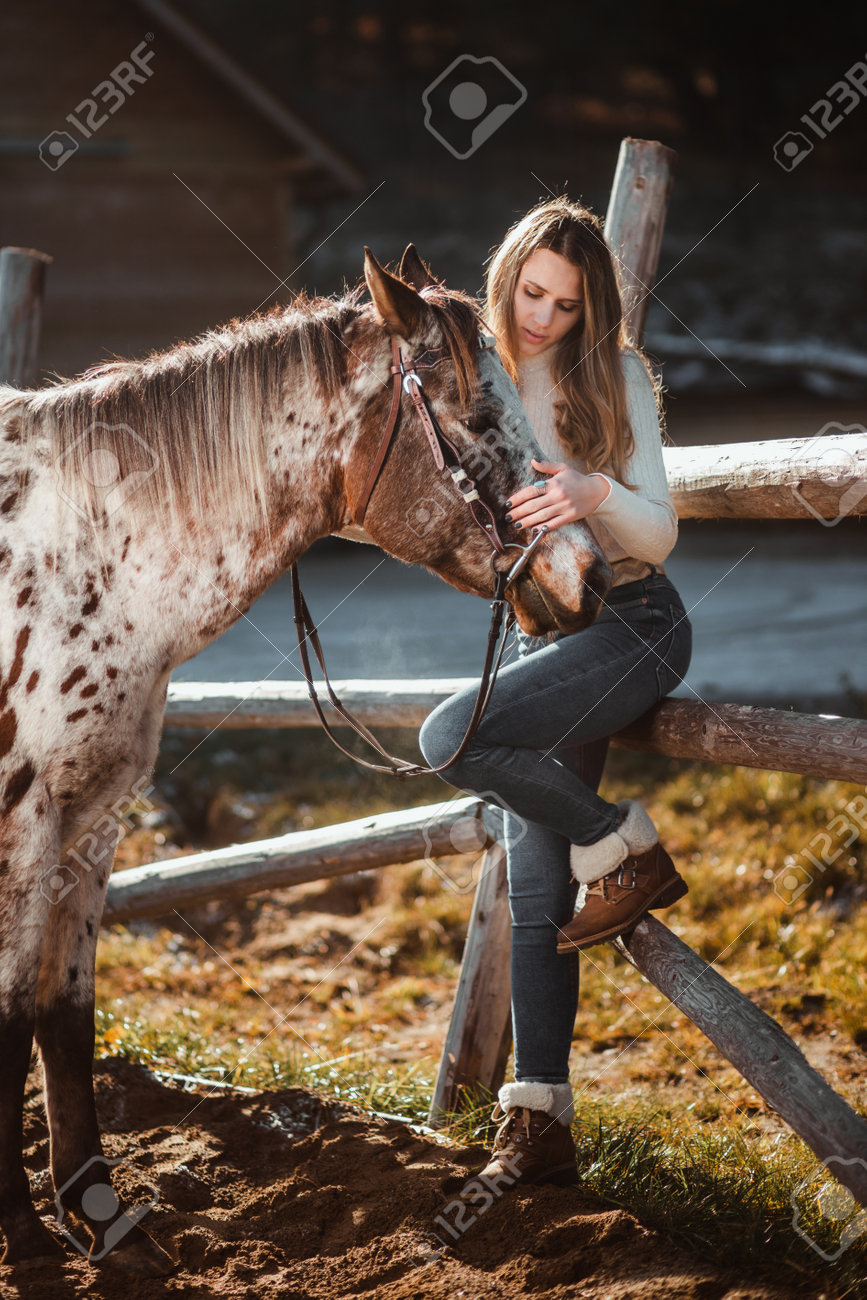 Beautiful young girl posing with her horse in the nature. Sunny autumn day. - 161105286