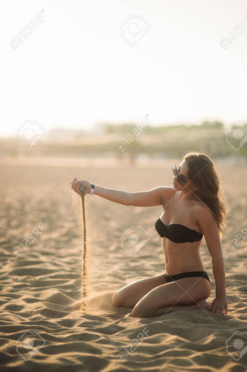 Sexy girl sunbathing on a sandy beach, lying on the lounger. Sunset silhouette - 82434865