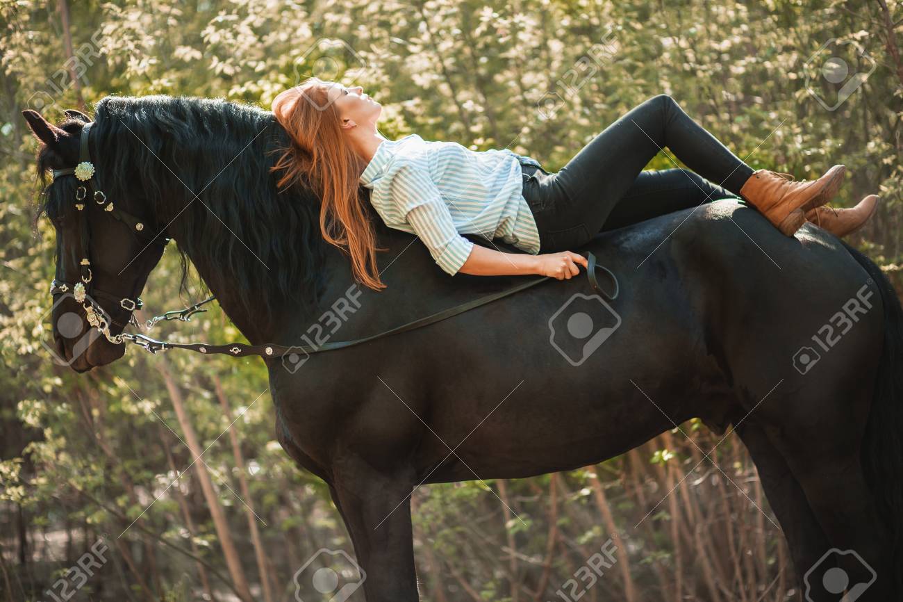 Young rider girl with long hair lying on horse neck - 94450257