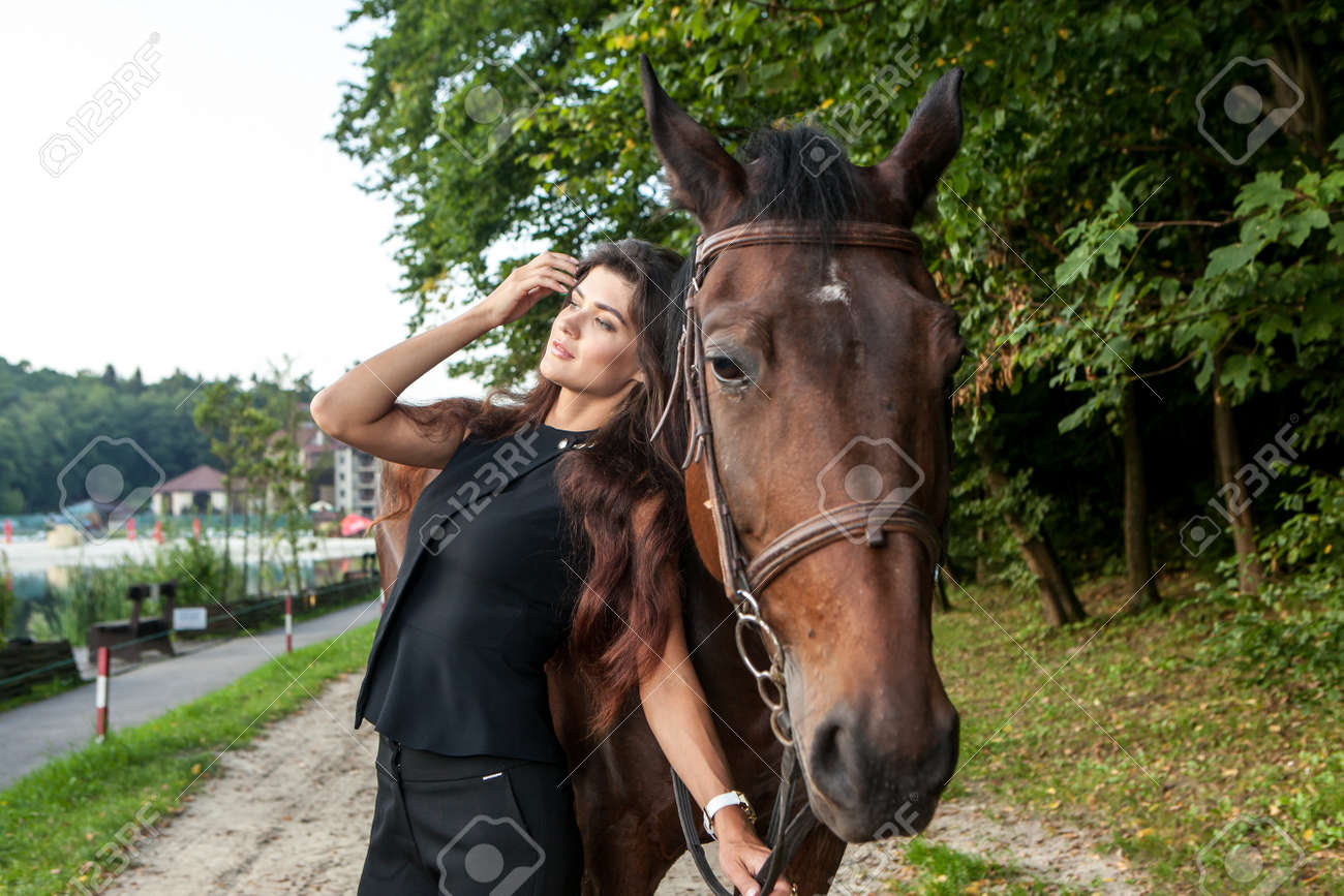 Pretty young woman and a brown horse outdoor - 98861805