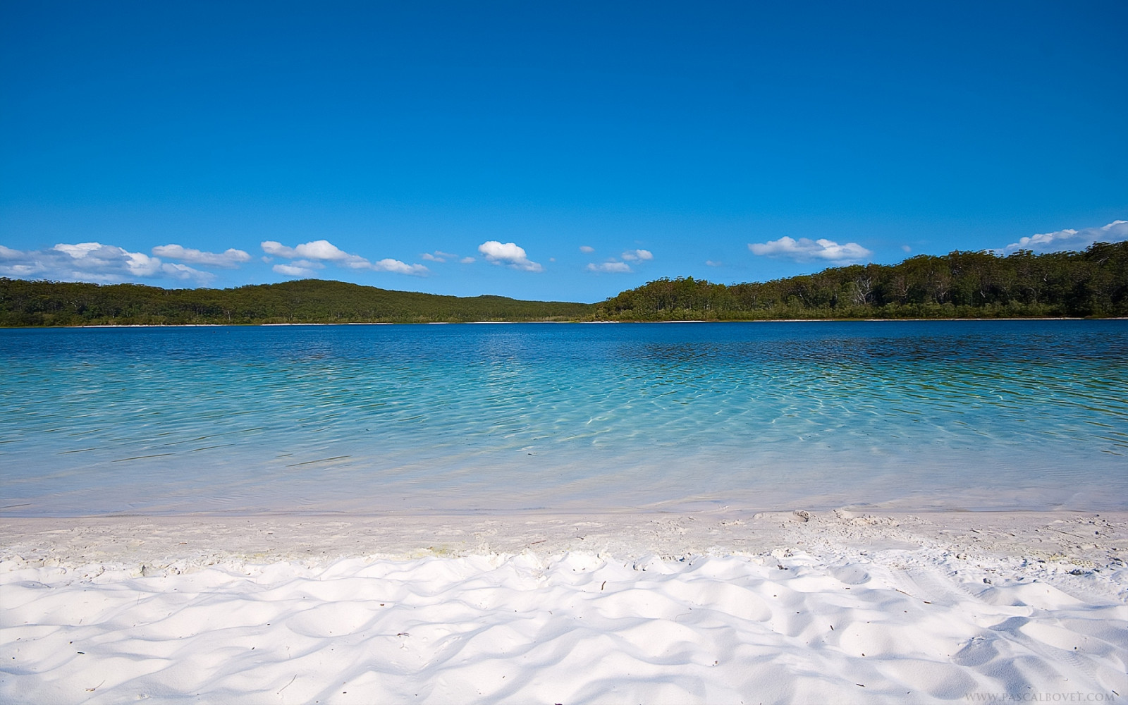 sunlight, landscape, sea, bay, lake, water, shore, sand, reflection, sky, beach, calm, coast, Sun, harbor, horizon, lagoon, heat, Caribbean, gulf, vacation, cloud, tree, mountain, ocean, tropics, reservoir, daytime, body of water, mountain range, azure, coastal and oceanic landforms